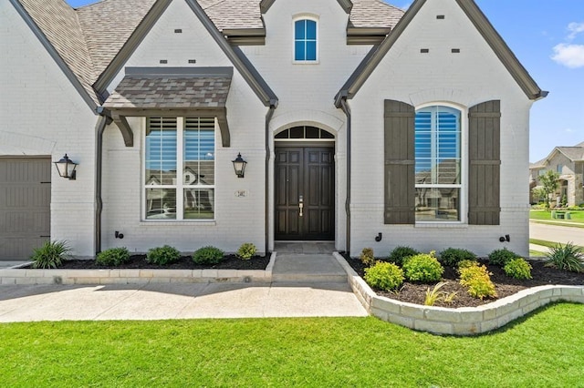 entrance to property featuring a yard and a garage