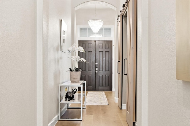 interior space with a barn door, light wood-type flooring, and a chandelier