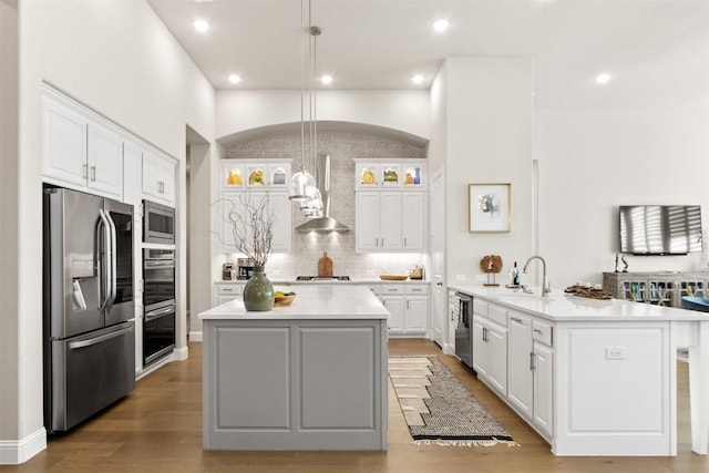 kitchen featuring stainless steel appliances, an island with sink, pendant lighting, and white cabinetry