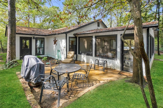 rear view of property with a lawn, a patio area, and a sunroom