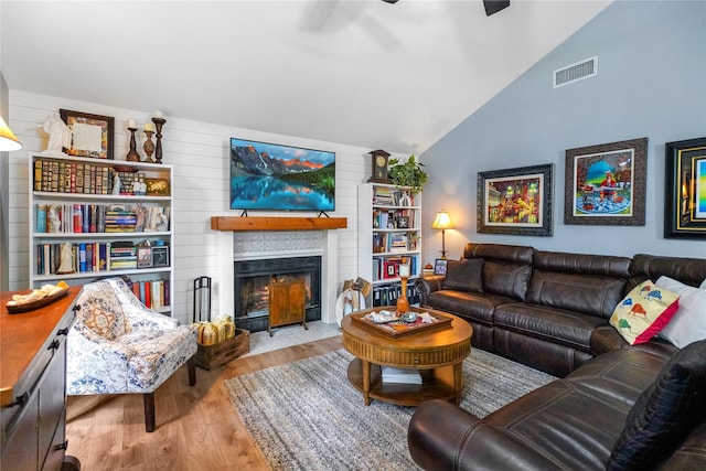 living room with a fireplace, light hardwood / wood-style floors, vaulted ceiling, and ceiling fan