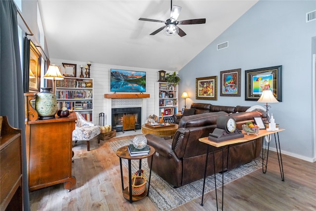 living room with hardwood / wood-style floors, ceiling fan, a large fireplace, and vaulted ceiling