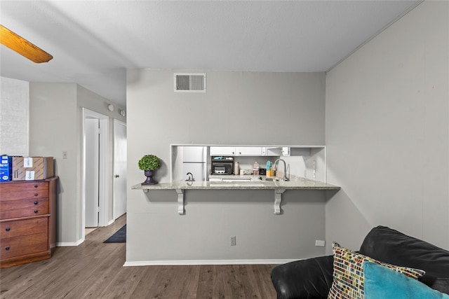 kitchen with dark wood-type flooring, white refrigerator, sink, white cabinetry, and kitchen peninsula