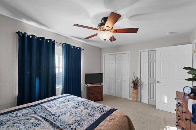 carpeted bedroom featuring multiple closets and ceiling fan