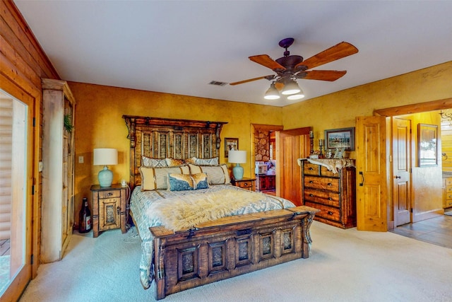 bedroom with ceiling fan, wooden walls, and light colored carpet