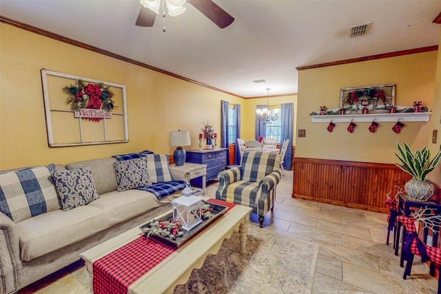 living room with wood walls, ceiling fan with notable chandelier, and ornamental molding