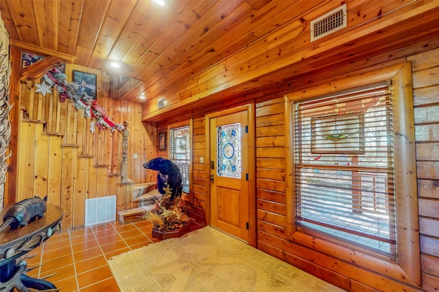 tiled entrance foyer featuring a healthy amount of sunlight, wooden ceiling, and wood walls