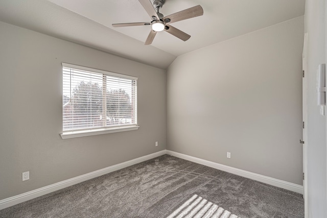 spare room with dark carpet, vaulted ceiling, and ceiling fan