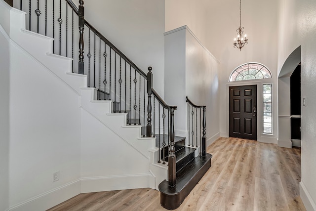 foyer entrance featuring a chandelier, a high ceiling, and light wood-type flooring