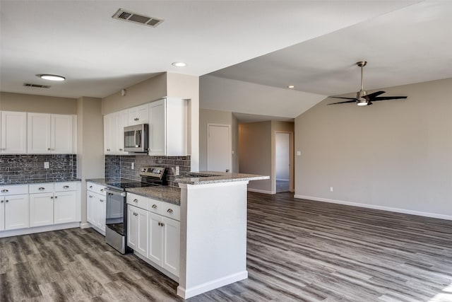 kitchen featuring kitchen peninsula, tasteful backsplash, stainless steel appliances, white cabinetry, and lofted ceiling