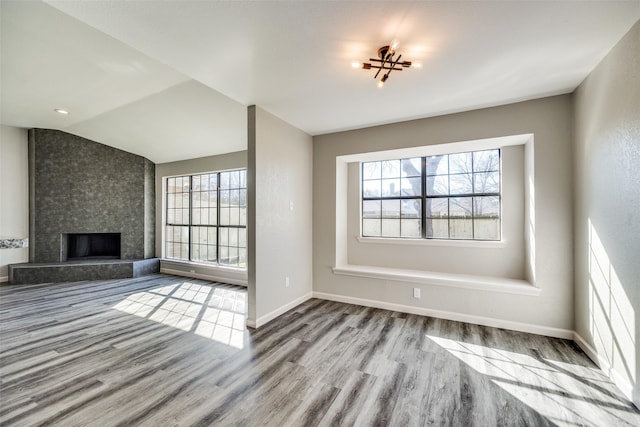 unfurnished living room featuring a large fireplace, light hardwood / wood-style floors, vaulted ceiling, and a healthy amount of sunlight