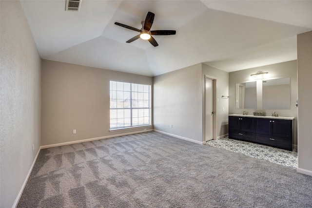 unfurnished bedroom featuring ceiling fan, a raised ceiling, carpet floors, and ensuite bath