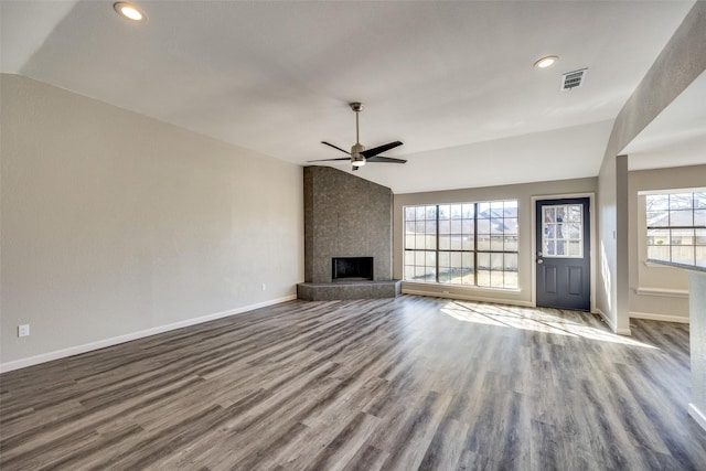 unfurnished living room with hardwood / wood-style floors, a large fireplace, vaulted ceiling, and plenty of natural light