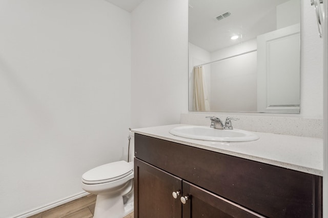 bathroom featuring curtained shower, hardwood / wood-style floors, vanity, and toilet