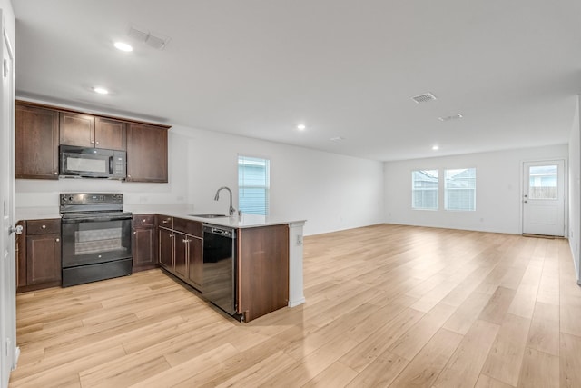 kitchen with kitchen peninsula, light hardwood / wood-style flooring, black appliances, and sink