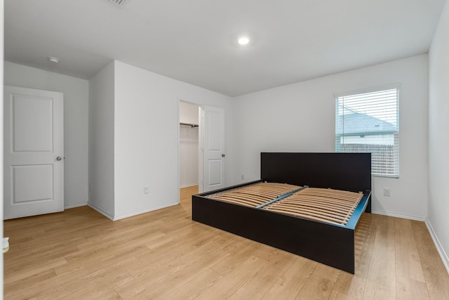 bedroom with a spacious closet, light hardwood / wood-style flooring, and a closet