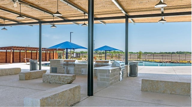 view of patio featuring an outdoor kitchen, a fenced in pool, and grilling area