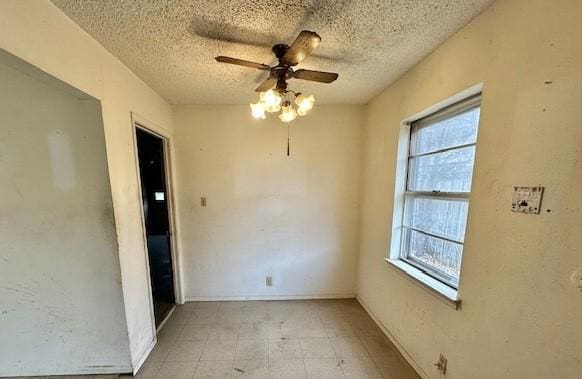 unfurnished room with ceiling fan and a textured ceiling