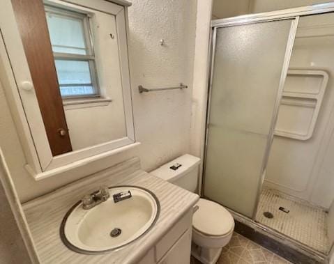 bathroom featuring vanity, toilet, and a shower with shower door