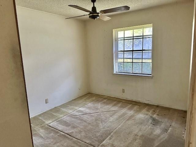 spare room featuring a textured ceiling, light colored carpet, and ceiling fan