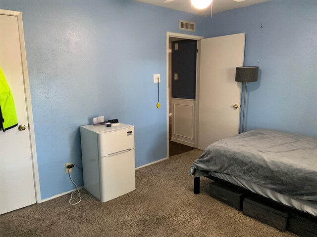 bedroom with ceiling fan, refrigerator, and dark carpet