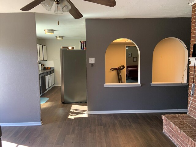 unfurnished living room with a fireplace, ceiling fan, and dark wood-type flooring