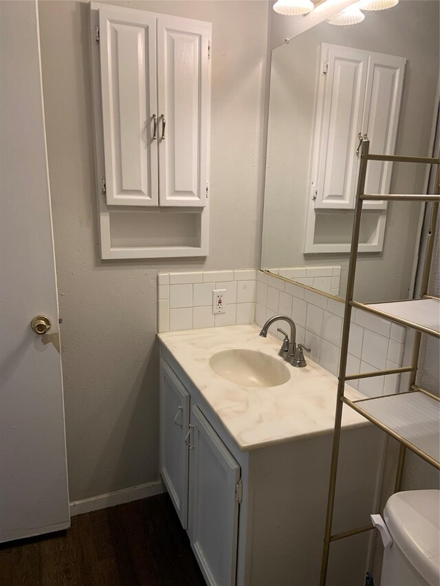 bathroom featuring hardwood / wood-style flooring, vanity, toilet, and decorative backsplash