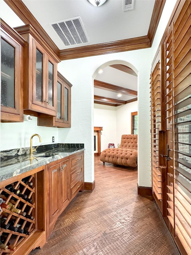 bar featuring crown molding, sink, beamed ceiling, and dark stone counters