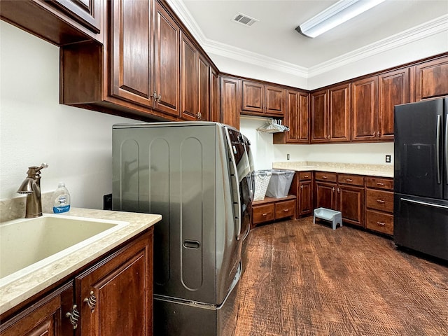 laundry area featuring dark wood-type flooring, crown molding, sink, and cabinets