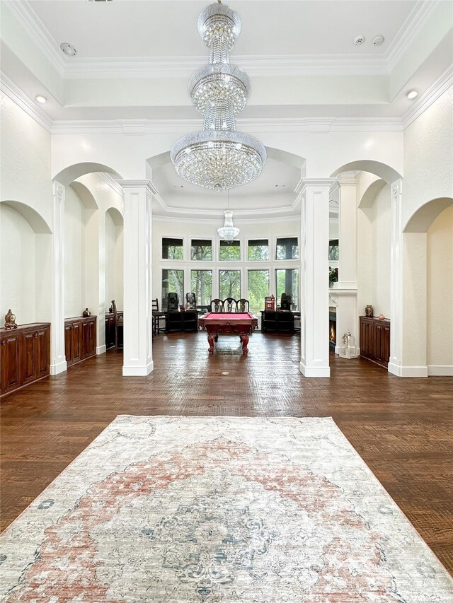 entryway with ornate columns, ornamental molding, a notable chandelier, dark hardwood / wood-style floors, and pool table