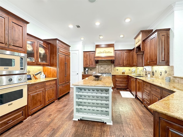 kitchen with stainless steel microwave, oven, decorative backsplash, light stone countertops, and a kitchen island