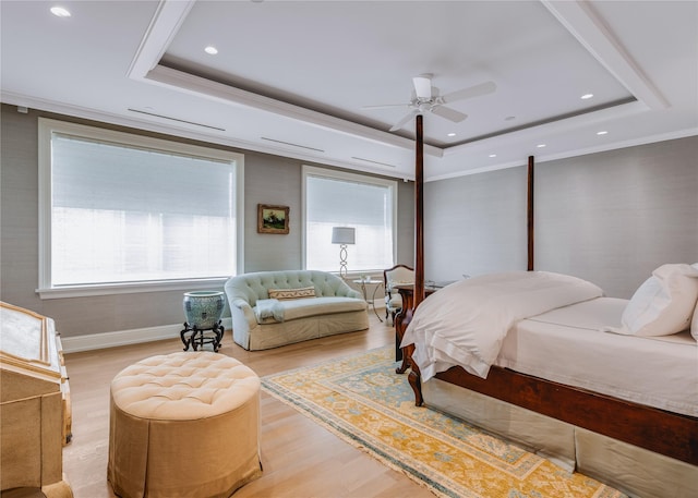 bedroom with ceiling fan, wood-type flooring, a tray ceiling, and ornamental molding