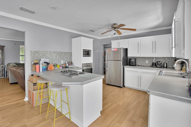 kitchen with a breakfast bar, sink, white cabinets, light hardwood / wood-style floors, and stainless steel appliances