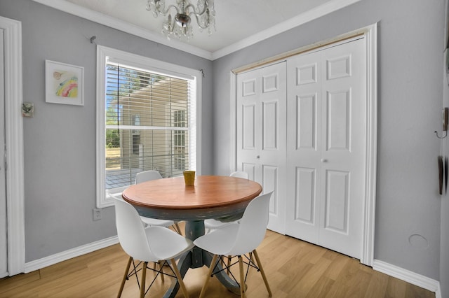 dining area with an inviting chandelier, ornamental molding, and light wood-type flooring