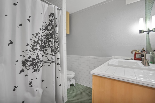 bathroom with tile walls, a shower with shower curtain, vanity, tile patterned floors, and toilet