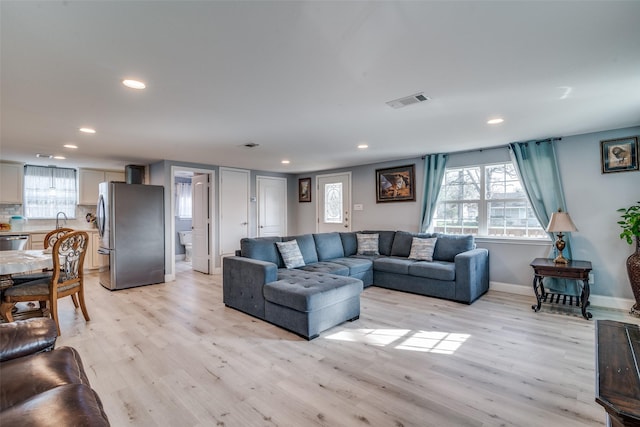 living room with light hardwood / wood-style floors and sink