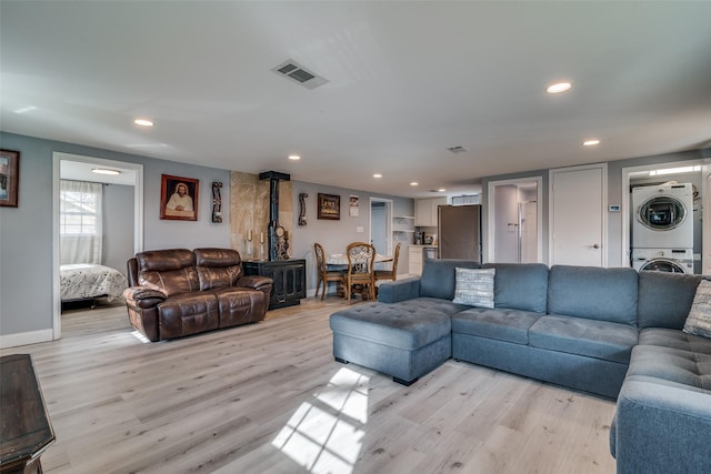 living room featuring stacked washer / drying machine and light hardwood / wood-style floors