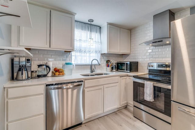 kitchen with appliances with stainless steel finishes, tasteful backsplash, decorative light fixtures, wall chimney range hood, and sink