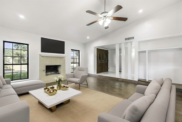 living room featuring ornamental molding, wood-type flooring, a fireplace, and vaulted ceiling