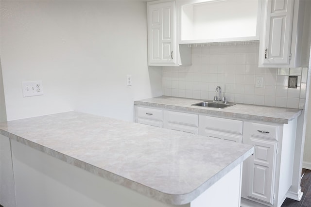 kitchen featuring kitchen peninsula, decorative backsplash, white cabinetry, and sink