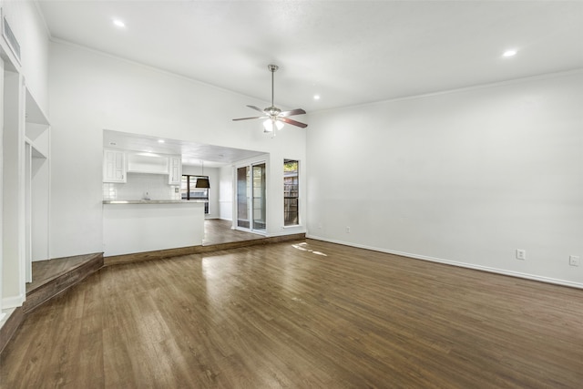 unfurnished living room featuring dark hardwood / wood-style flooring, ceiling fan, and ornamental molding