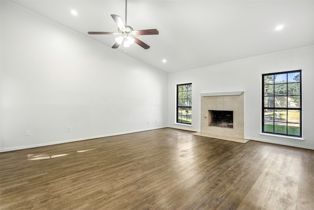 unfurnished living room with lofted ceiling, a tile fireplace, dark hardwood / wood-style floors, ceiling fan, and ornamental molding