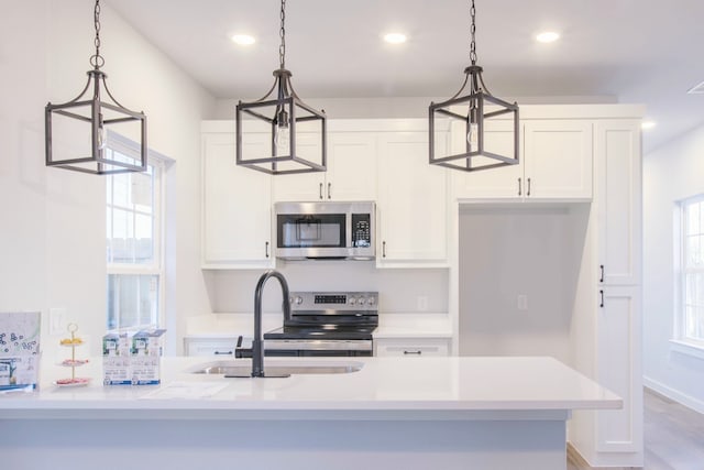 kitchen with hanging light fixtures, white cabinets, appliances with stainless steel finishes, and sink