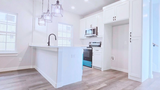 kitchen featuring appliances with stainless steel finishes, sink, white cabinetry, and decorative light fixtures