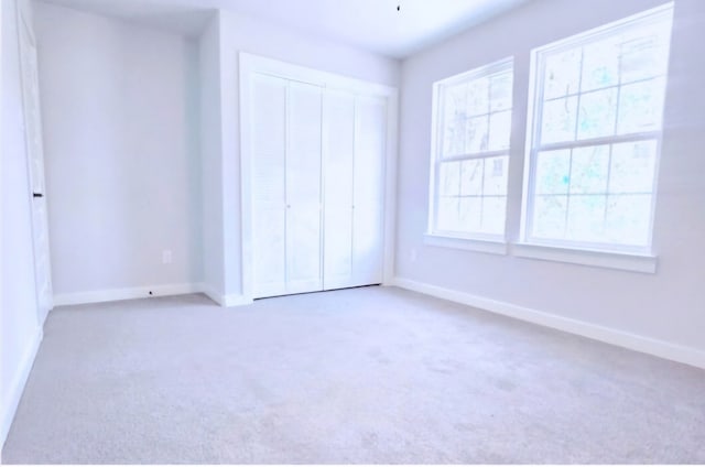 unfurnished bedroom featuring light carpet and a closet