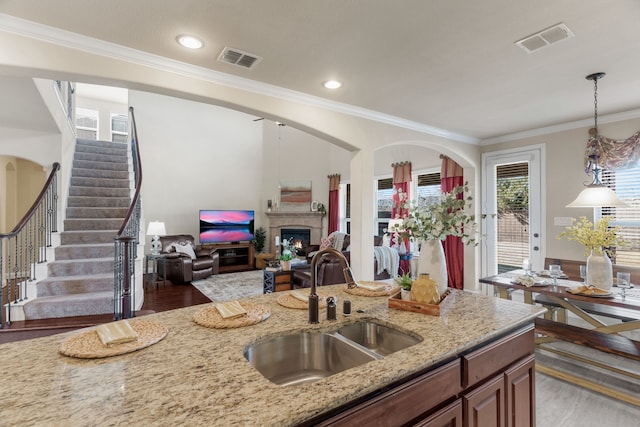 10014 Edgeway Cir, Rowlett, TX 75089 - kitchen featuring a sink, light stone countertops, ornamental molding, hanging light fixtures, and a lit fireplace