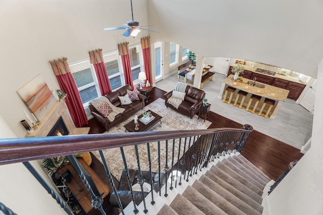 10014 Edgeway Cir, Rowlett, TX 75089 - stairway with wood finished floors, a ceiling fan, a lit fireplace, arched walkways, and a towering ceiling