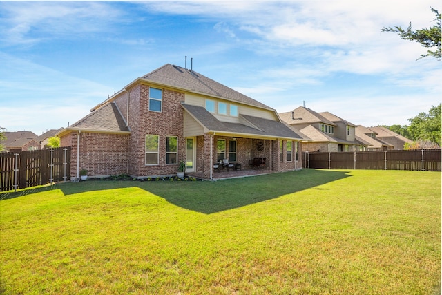 rear view of house featuring brick siding, a yard, a fenced backyard, and roof with shingles