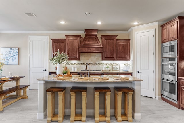 10014 Edgeway Cir, Rowlett, TX 75089 - kitchen featuring stainless steel appliances, custom range hood, a breakfast bar, an island with sink, and crown molding