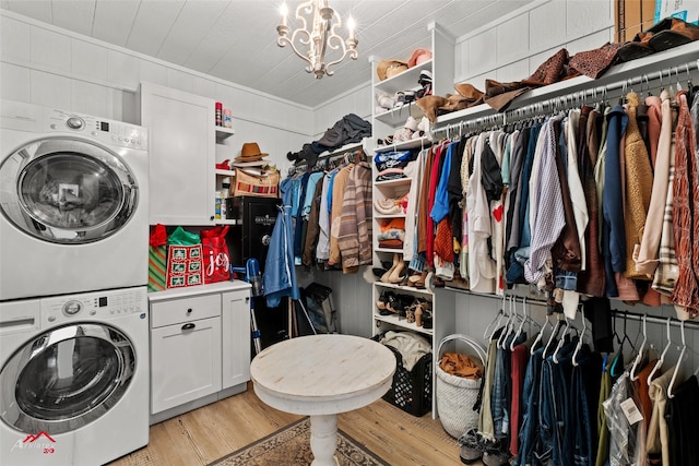 laundry room with stacked washer and dryer, an inviting chandelier, and light wood-type flooring